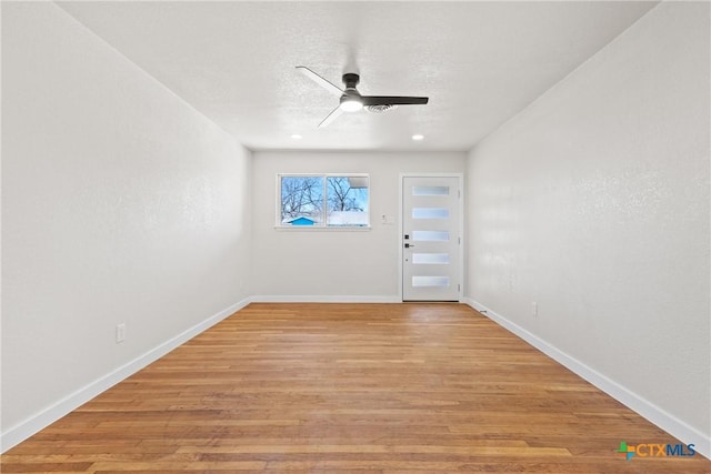 interior space with light wood-style flooring, a textured ceiling, baseboards, and a ceiling fan