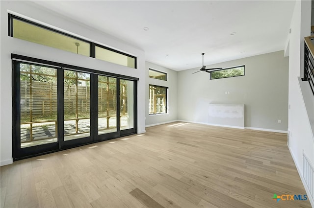 unfurnished living room featuring light wood-type flooring, a wealth of natural light, and ceiling fan