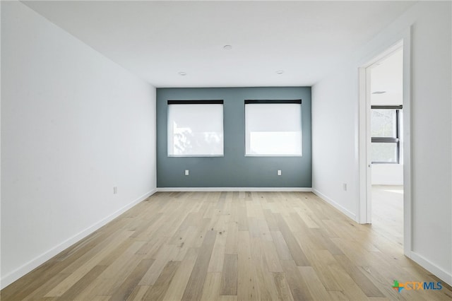 spare room featuring light wood-type flooring and a healthy amount of sunlight