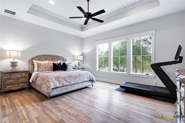 bedroom with ornamental molding, a raised ceiling, ceiling fan, and light wood-type flooring