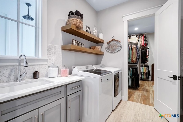 laundry room with cabinets, sink, washing machine and dryer, and light hardwood / wood-style flooring