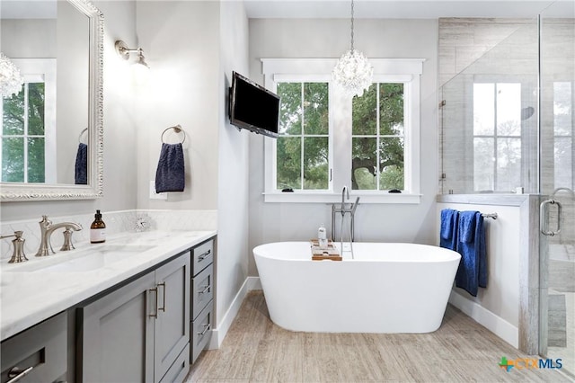 bathroom featuring vanity, hardwood / wood-style flooring, shower with separate bathtub, and an inviting chandelier