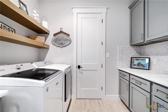 clothes washing area featuring cabinets, washer and dryer, and light hardwood / wood-style floors