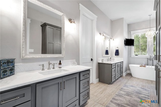 bathroom with a tub to relax in, a chandelier, and vanity