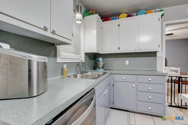 kitchen featuring light tile patterned floors, white cabinetry, stainless steel dishwasher, and sink