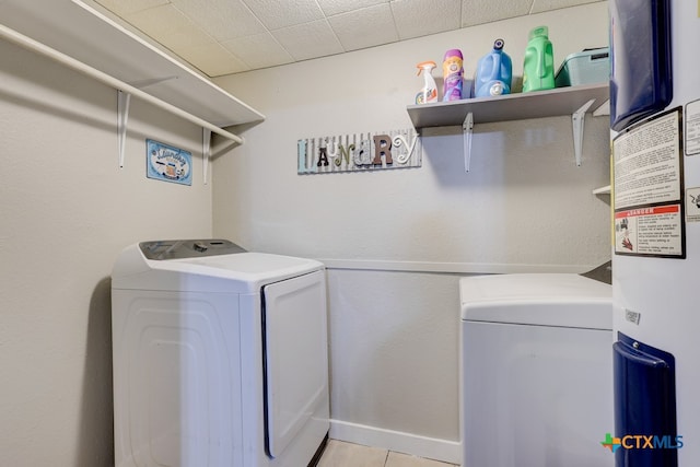 clothes washing area with independent washer and dryer, light tile patterned floors, and water heater