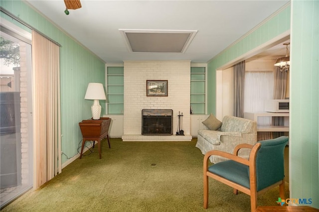 sitting room featuring built in features, ornamental molding, carpet, and a fireplace