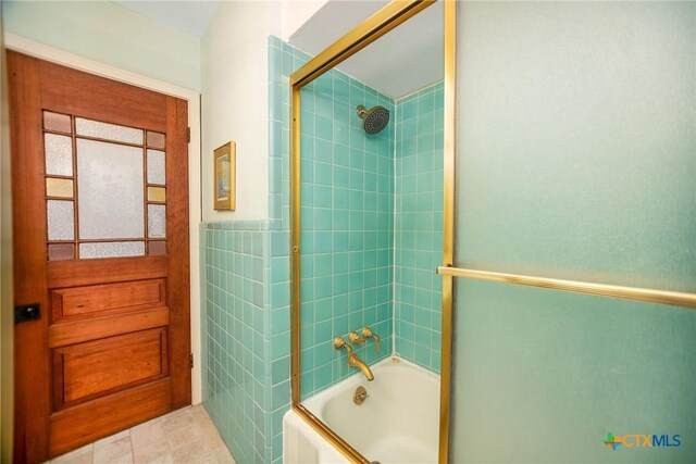 full bathroom featuring tile walls and combined bath / shower with glass door