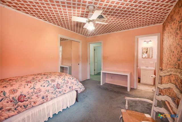 carpeted bedroom with a closet, ceiling fan, and ensuite bath
