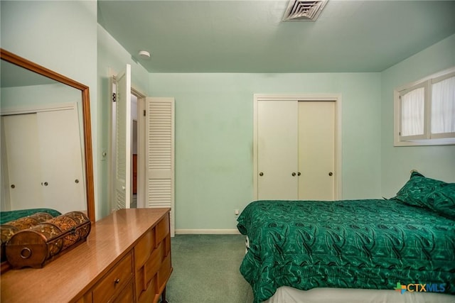 bedroom with dark carpet, baseboards, visible vents, and two closets