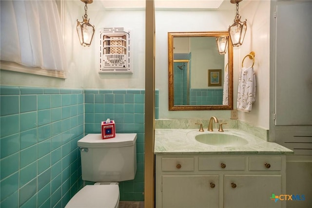 bathroom with a wainscoted wall, toilet, vanity, and tile walls