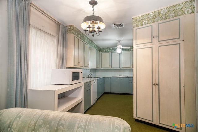 kitchen featuring light countertops, visible vents, white appliances, a sink, and a notable chandelier