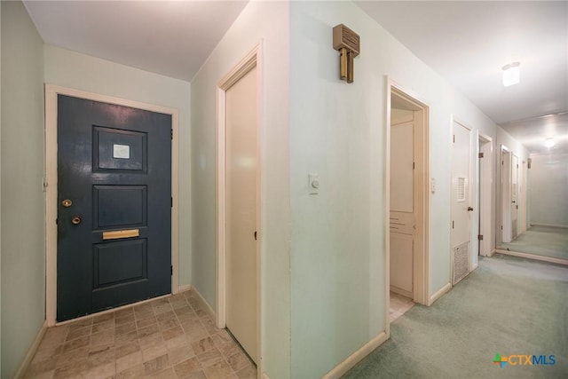 foyer featuring baseboards and light colored carpet