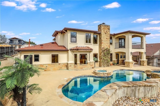 back of house featuring a balcony, a patio area, and a pool with hot tub