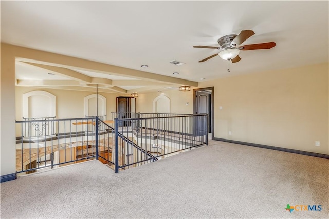 spare room with carpet, ceiling fan, and beamed ceiling