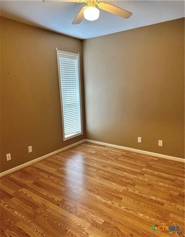 spare room featuring wood finished floors, ceiling fan, and baseboards