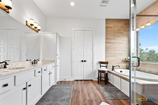 213 Lets Roll Dr, Fischer, TX 78623 - bathroom featuring double vanity, a garden tub, a closet, wood finished floors, and a stall shower