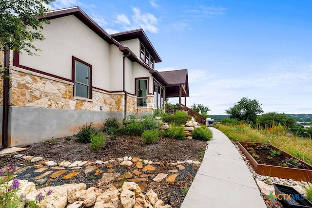 213 Lets Roll Dr, Fischer, TX 78623 - view of property exterior featuring stone siding, a garden, stucco siding, and stairway