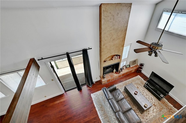 living room featuring high vaulted ceiling, dark hardwood / wood-style flooring, ceiling fan, and a tile fireplace