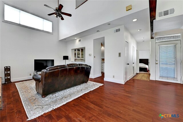 living room with dark wood-type flooring, a high ceiling, and ceiling fan