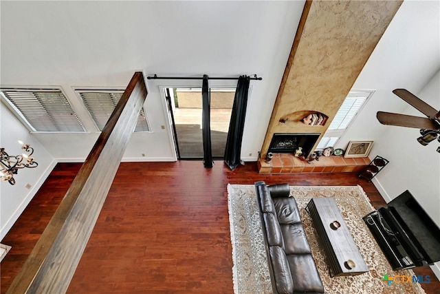 living room with dark wood-type flooring, a wealth of natural light, and a tiled fireplace