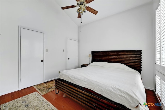 bedroom with dark wood-type flooring, ceiling fan, and high vaulted ceiling