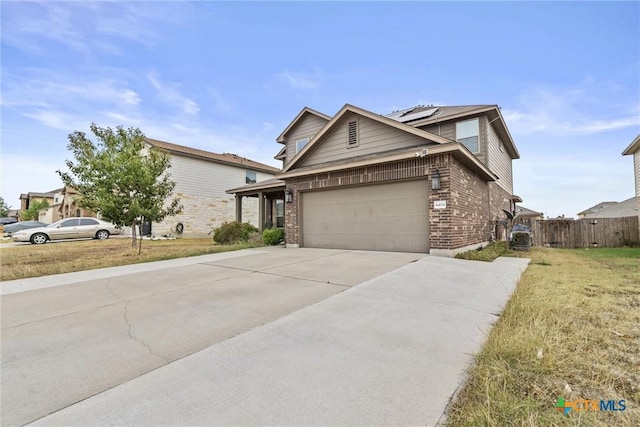 view of front of house with concrete driveway, solar panels, an attached garage, fence, and brick siding