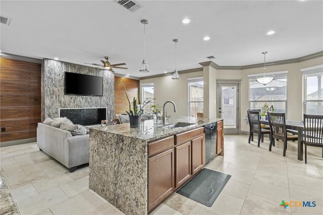 kitchen with black dishwasher, visible vents, an accent wall, a sink, and light stone countertops