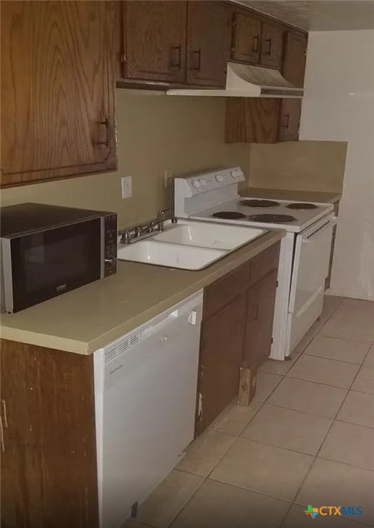 kitchen featuring extractor fan, white appliances, sink, and light tile patterned floors