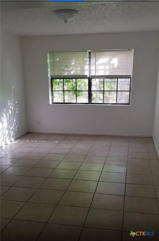 empty room featuring a textured ceiling and tile patterned floors