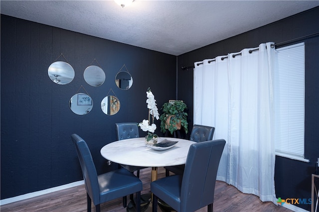 dining room featuring wood-type flooring and a textured ceiling