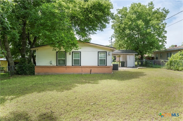 rear view of house featuring a lawn and a shed