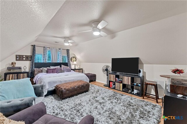 bedroom featuring wood-type flooring, lofted ceiling, a textured ceiling, and ceiling fan