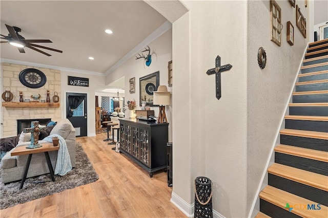 living room featuring crown molding, ceiling fan, a fireplace, and light hardwood / wood-style flooring