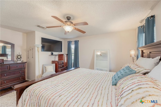 bedroom featuring hardwood / wood-style floors, ceiling fan, and a textured ceiling