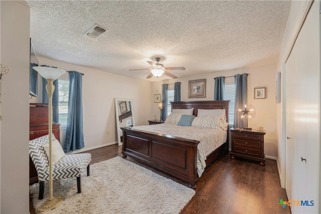 bedroom featuring dark wood-type flooring, a textured ceiling, and ceiling fan