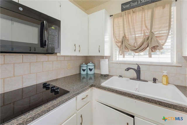 kitchen with white cabinetry, sink, black appliances, and tasteful backsplash