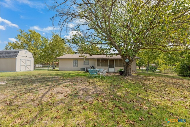 back of property with a shed, central air condition unit, and a yard