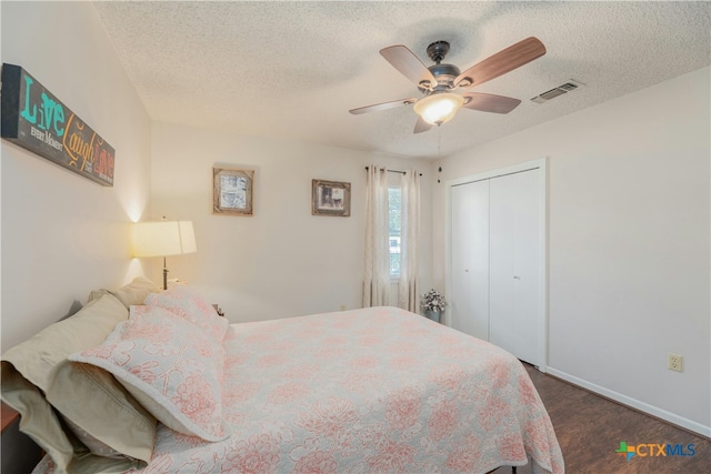 bedroom featuring ceiling fan, a textured ceiling, a closet, and dark hardwood / wood-style flooring