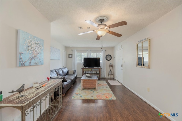 living room with dark wood-type flooring, a textured ceiling, and ceiling fan