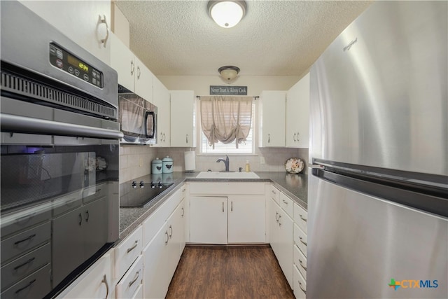 kitchen featuring white cabinets, sink, black appliances, and backsplash