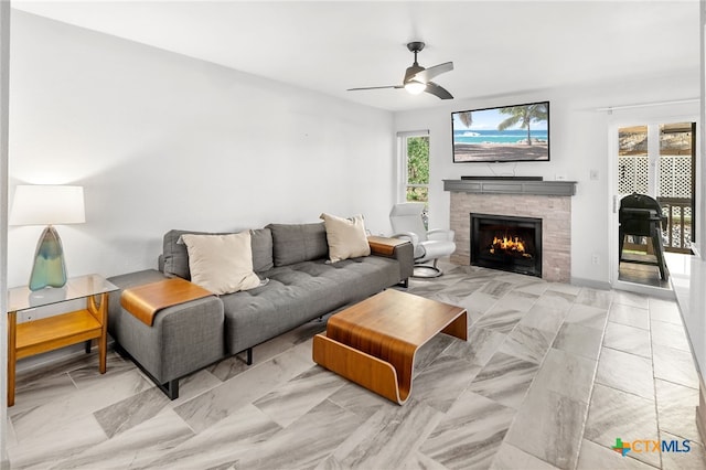 living room with ceiling fan and a lit fireplace