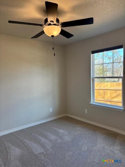 carpeted spare room featuring ceiling fan and a textured ceiling