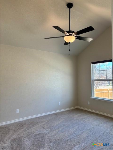 spare room with vaulted ceiling, carpet, and ceiling fan