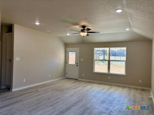 interior space with ceiling fan, light wood-type flooring, a textured ceiling, and vaulted ceiling