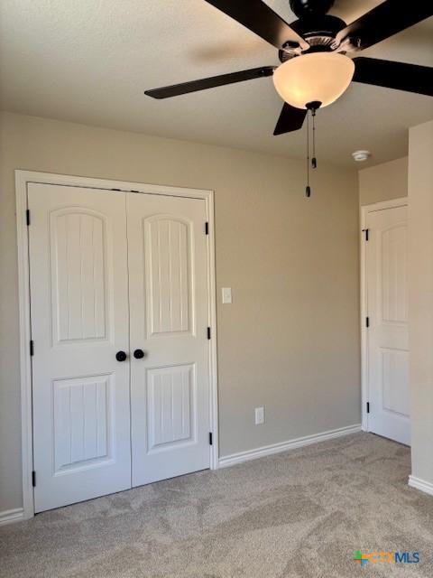 unfurnished bedroom featuring ceiling fan, light colored carpet, and a closet