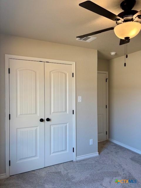 unfurnished bedroom with a closet, ceiling fan, and light colored carpet