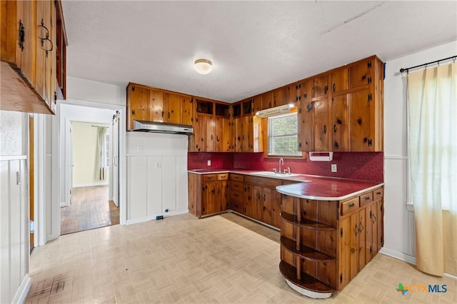 1820 S 49th St, Temple, TX 76504 - kitchen featuring brown cabinetry, a peninsula, open shelves, tasteful backsplash, and light countertops