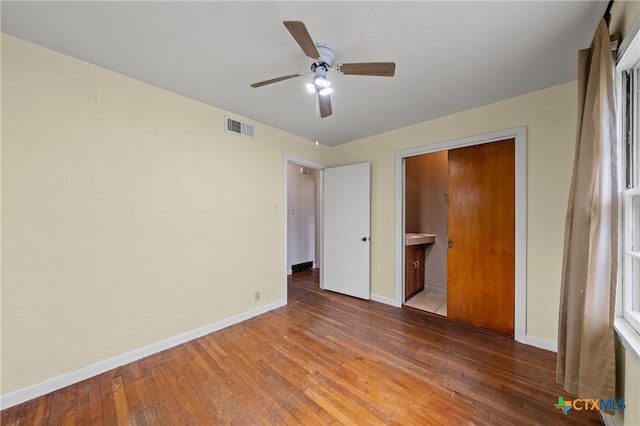 1820 S 49th St, Temple, TX 76504 - unfurnished bedroom with hardwood / wood-style floors, ceiling fan, and connected bathroom