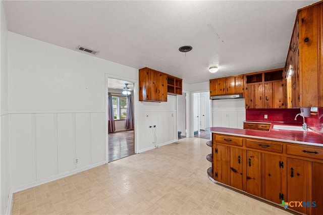 1820 S 49th St, Temple, TX 76504 - kitchen featuring brown cabinets, a decorative wall, a wainscoted wall, and light countertops